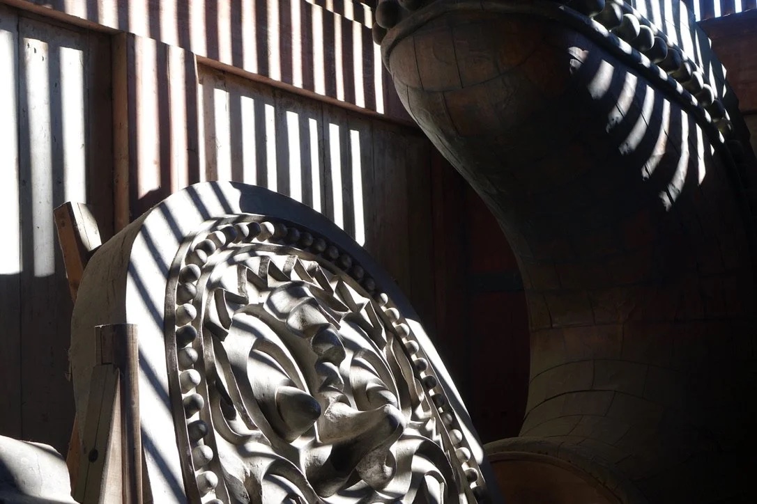 A guardian statue in slatted window light.