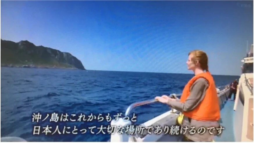 Lindsey in a life vest on the deck of a boat approaching the island of Okinoshima, from the FBS documentary.